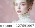 Woman with porcelain skin poses gracefully against a soft pink backdrop 127691007