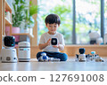 Boy engages with a voice assistant robot during playtime indoors 127691008