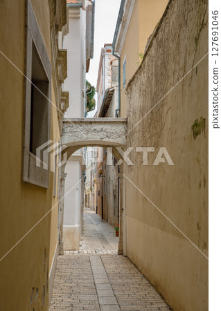 Narrow stone alley with arch. Old European town Porec, Croatia. 127691046