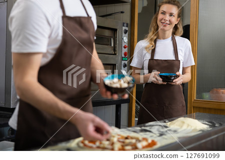 Man preparing pizza with woman 127691099
