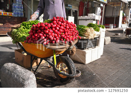 Large heap of fresh radish vegetable displayed on street in wheelbarrow - fruit and vegetables are usually sold on streets at Jordan Large heap of fresh radish vegetable displayed on street in wheelbarrow - fruit and vegetables are usually sold on streets at Jordan 127691250