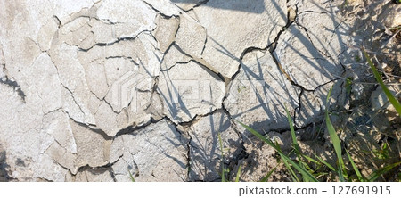 Cracked Dried Earth Showing Signs of Drought in a Barren Landscape During Midday Sun 127691915