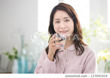一名穿著睡衣的年輕女子醒來後喝水 127691934
