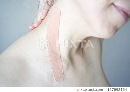 Close-up of elastic beige kinesiology tape on female caucasian shoulder Close-up of elastic beige kinesiology tape on female caucasian shoulder 127692164