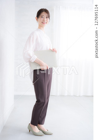 A woman in a pink sheer shirt holding a file on a white background, looking at the camera. Real estate job changes, professional services, human resources, etc. A woman in a pink sheer shirt holding a file on a white background, looking at the camera. Real estate job changes, professional services, human resources, etc. 127695114