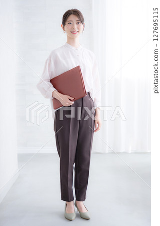 A woman in a pink sheer shirt holding a file on a white background, looking at the camera. Real estate job changes, professional services, human resources, etc. A woman in a pink sheer shirt holding a file on a white background, looking at the camera. Real estate job changes, professional services, human resources, etc. 127695115