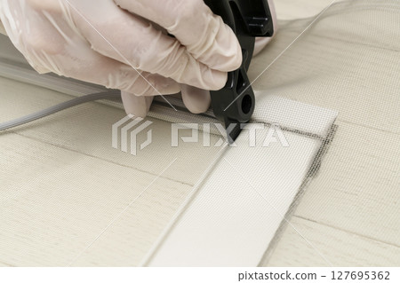 更換紗門:剪開紗門並用滾筒將繩子推入框架。 更換紗門:剪開紗門並用滾筒將繩子推入框架。 127695362
