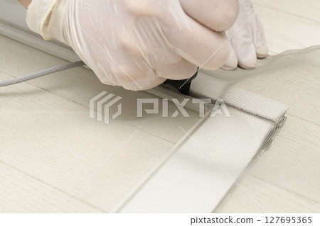 更換紗門:剪開紗門並用滾筒將繩子推入框架。 更換紗門:剪開紗門並用滾筒將繩子推入框架。 127695365