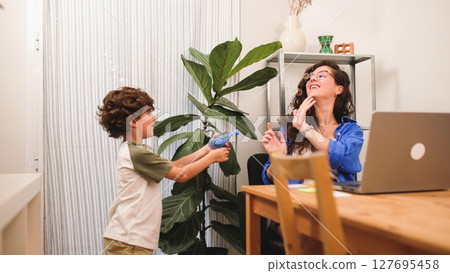 Happy freelancer enjoying soap bubbles with son while working from home Happy freelancer enjoying soap bubbles with son while working from home 127695458