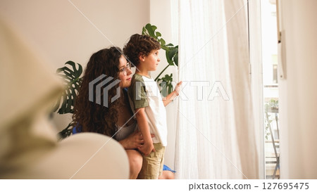 Mother and son looking out window at home Mother and son looking out window at home 127695475
