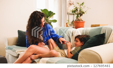 Mother and son sharing a playful moment on the sofa Mother and son sharing a playful moment on the sofa 127695481