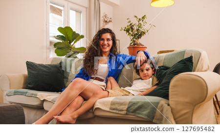 Mother and son relaxing on sofa at home, enjoying quality time together Mother and son relaxing on sofa at home, enjoying quality time together 127695482