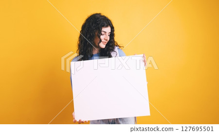 Young student woman showing blank whiteboard on yellow background Young student woman showing blank whiteboard on yellow background 127695501