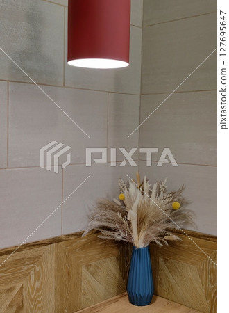 stylish corner featuring blue vase dried flowers illuminated by soft red light in interior. closeup. 127695647