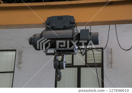 Industrial overhead crane hoist mechanism with wire rope and hook in a warehouse Industrial overhead crane hoist mechanism with wire rope and hook in a warehouse 127696610