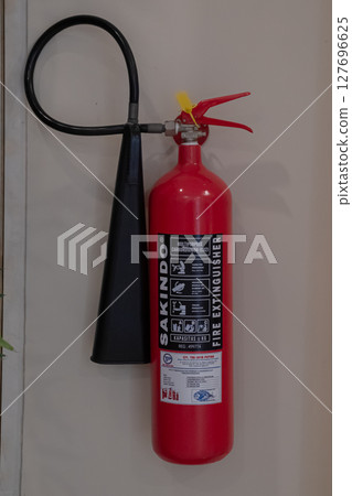 Red Fire Extinguisher Mounted on Wall for Emergency Fire Safety at Mataram, Indonesia on November 9, 2024 127696625