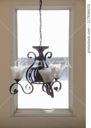 Close up view of a vintage-style chandelier against the bright natural light of a window Close up view of a vintage-style chandelier against the bright natural light of a window 127696628