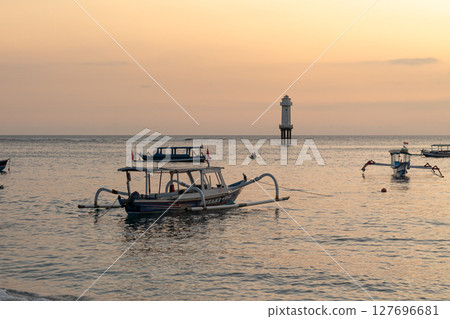 Serene ocean view with fishing boats and distant lighthouse at dusk 127696681