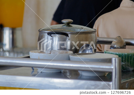 Close-up view of a large metal pot and serving bowls on a stainless steel buffet line 127696726