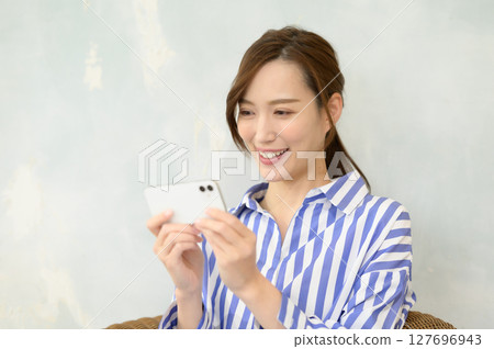 A woman watching video content on her smartphone 127696943