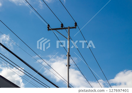 Utility Pole with Tangled Wires Against Blue Sky in Indonesia 127697401