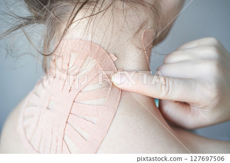 Female applying therapeutic kinesiology tape on neck for pain relief and muscle Female applying therapeutic kinesiology tape on neck for pain relief and muscle 127697506