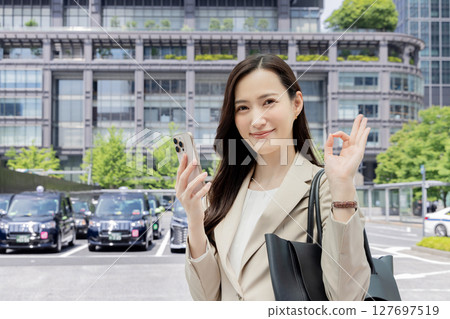 一位女商人拿著智慧型手機表示同意 127697519