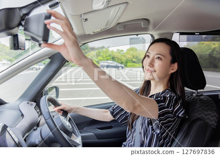 Young woman driving room mirror 127697836