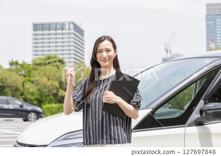 Woman pointing in front of a car Woman pointing in front of a car 127697848