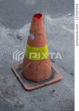 Weathered Road Marker - A Dilapidated Traffic Cone on Asphalt Weathered Road Marker - A Dilapidated Traffic Cone on Asphalt 127697916