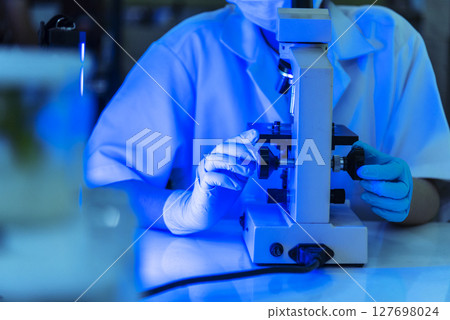 Female technician laboratory analyze genetic research. Woman scientist in lab look at science microscope medical test researching biology chemistry in blue light black background. Chemistry Medical Female technician laboratory analyze genetic research. Woman scientist in lab look at science microscope medical test researching biology chemistry in blue light black background. Chemistry Medical 127698024