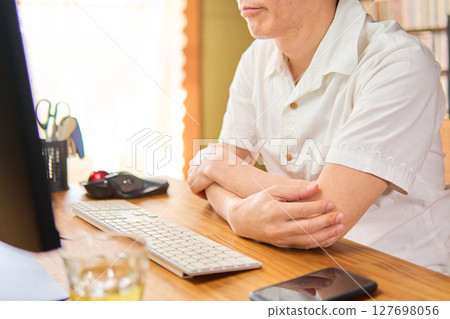 A man in his 50s staring at a computer screen and thinking A man in his 50s staring at a computer screen and thinking 127698056
