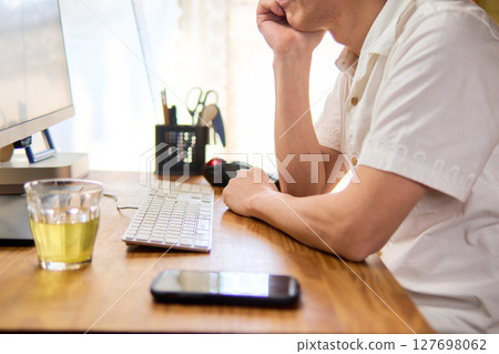 A man in his 50s staring at a computer screen and thinking A man in his 50s staring at a computer screen and thinking 127698062
