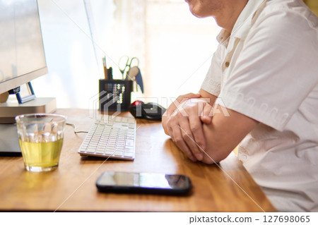 A man in his 50s staring at a computer screen and thinking A man in his 50s staring at a computer screen and thinking 127698065