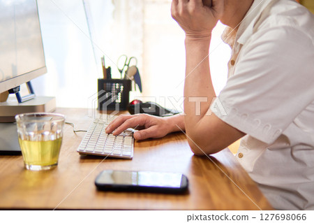 A man in his 50s staring at a computer screen and thinking A man in his 50s staring at a computer screen and thinking 127698066