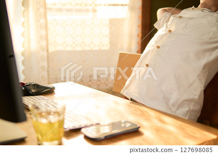 A man in his 50s stretching between computer work 127698085