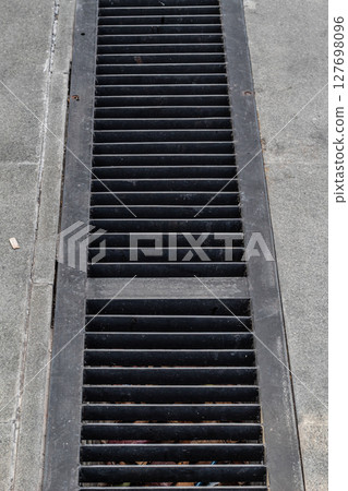 Urban Drainage System - Metal Grate Covering Street Gutter 127698096