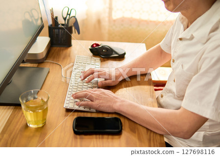 一名 50 多歲的男子正在電腦上打字 127698116