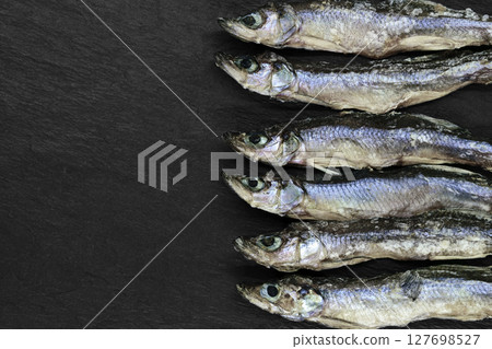 Dry small European smelt fishes on black stone background with copy space 127698527