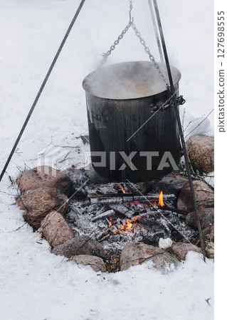Food preparation in huge black bowl on bonfire in winter time 127698555