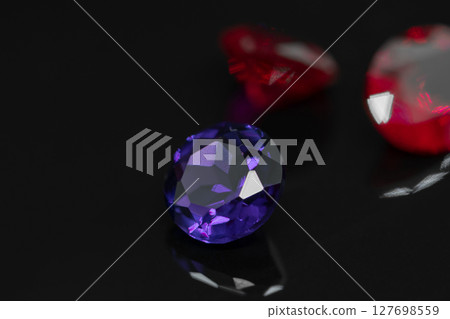Purple amethyst gemstone and red rubies on black reflective surface 127698559