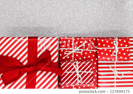 Various size wrapped in red paper with ornament Christmas gift boxes on shiny silver background 127699175