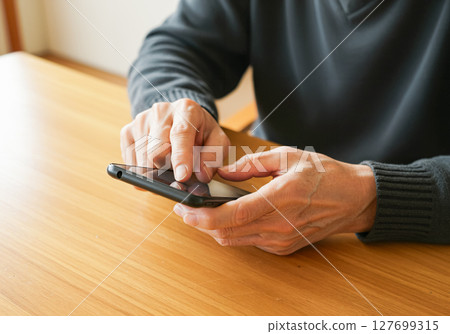 一位老人的手操作智慧型手機 一位老人的手操作智慧型手機 127699315