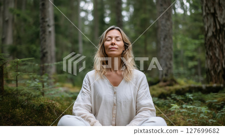 Peaceful woman meditating with closed eyes in serene forest setting for mindfulness and nature therapy 127699682