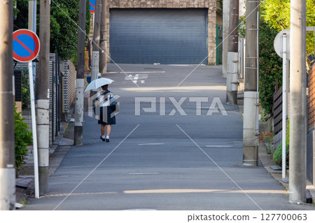 一名女學生撐著陽傘走路上學 一名女學生撐著陽傘走路上學 127700063