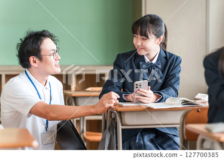 A teacher and a female student teaching using a smartphone (BYOD/ICT) 127700385