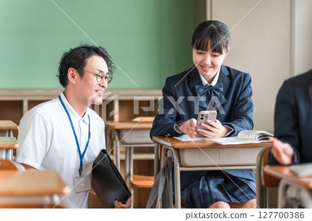 A teacher and a female student teaching using a smartphone (BYOD/ICT) A teacher and a female student teaching using a smartphone (BYOD/ICT) 127700386
