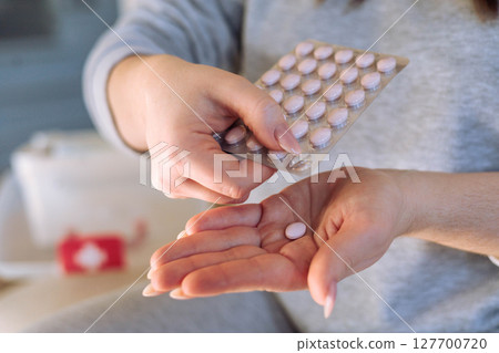 Female hands holding pink round hormonal contraceptive pill. Female hands holding pink round hormonal contraceptive pill. 127700720