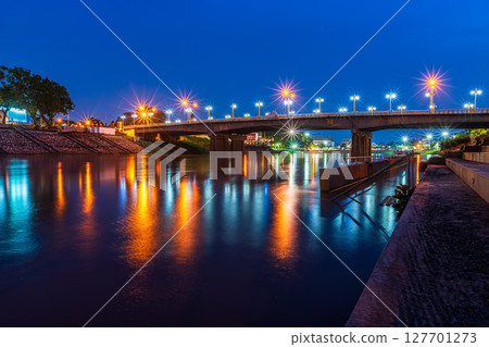 Beautiful lights water reflection full of banks of the Nan River at night on the bridge (Naresuan Bridge)at night in the park in Phitsanulok City,Thailand. 127701273