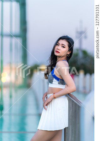 Portrait of beautiful athletic young asian woman in fashionable sportswear standing and having rest after exercise training on Route walking jogging or ride bicycle and exercise on the bridge. 127701331